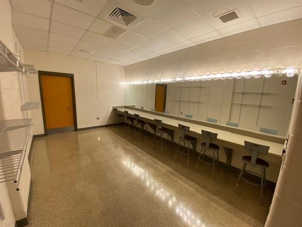 A dressing room with chairs aligned at the counter